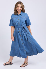 A model wearing the River Denim Dress in colour Midblue (Blue), from the front, showing the whole outfit