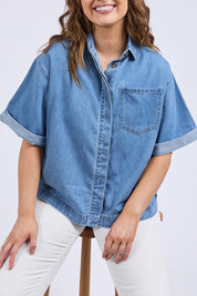 A model wearing the Annika Ss Denim Shirt in colour Midblue (Blue), from the front, cropped image