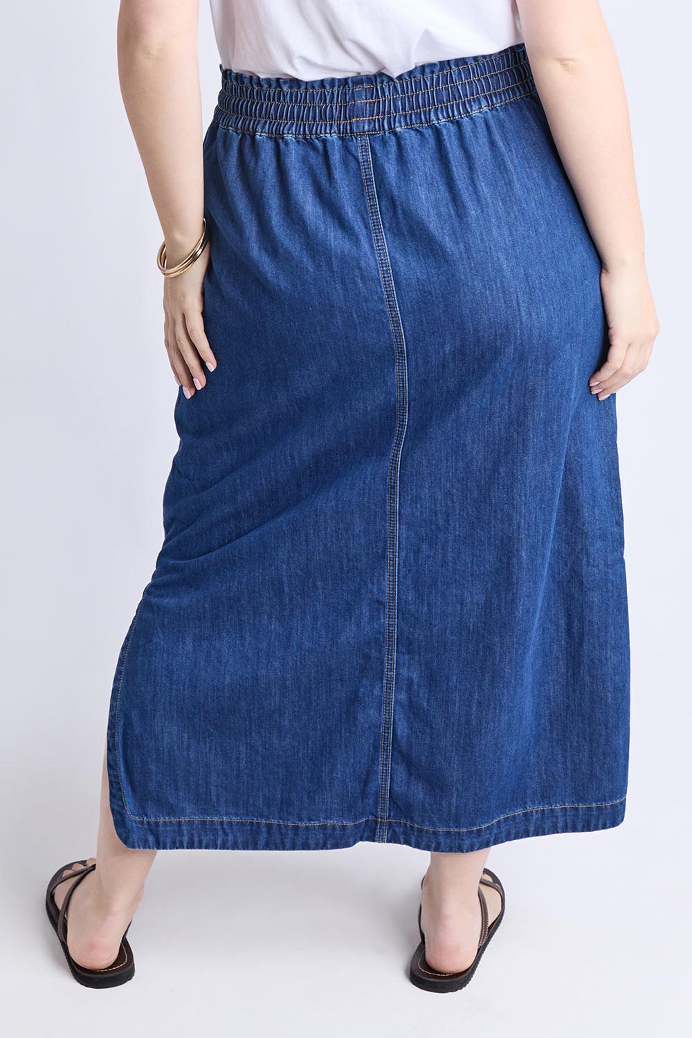 A model wearing the Clover Midi Denim Skirt in colour Midblue (Blue), from the back