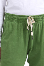 A model wearing the Fundamental Brunch Cotton Pant in colour Cedargreen (Green), from the front, cropped image