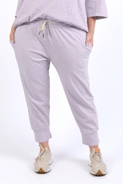 A model wearing the Fundamental Brunch Cotton Pant in colour Dustylilac (Purple), from the front, cropped image