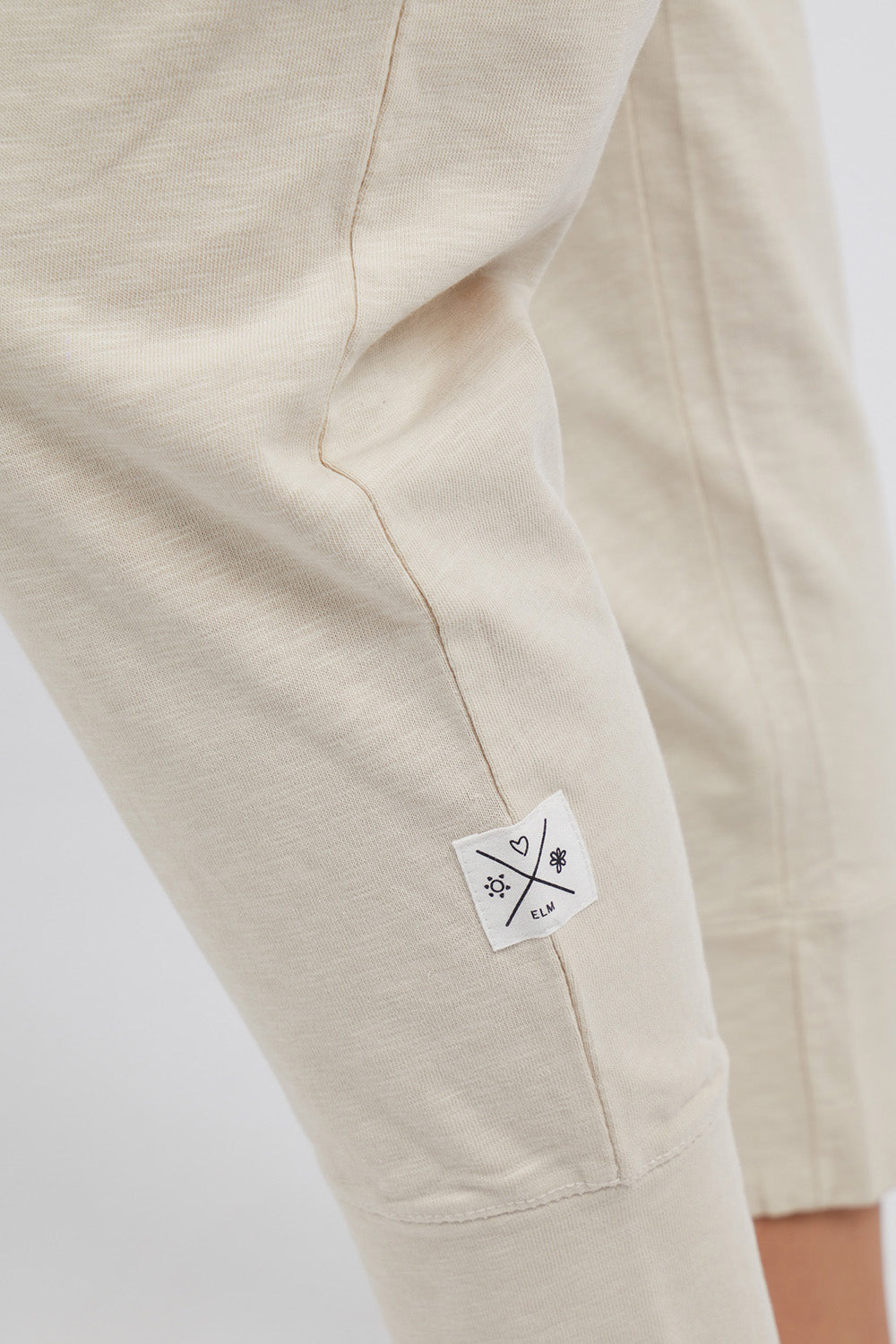A model wearing the Fundamental Brunch Cotton Pant in colour Linen, from the front, cropped image