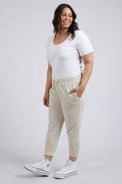 A model wearing the Fundamental Brunch Cotton Pant in colour Linen, from the front, showing the whole outfit