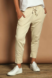 Model Katie wearing size 10 of the Fundamental Brunch Cotton Pant in colour Linen, from the front, cropped image