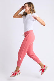 A model wearing the Fundamental Brunch Cotton Pant in colour Sugarcoral (Pink), from the front, showing the whole outfit
