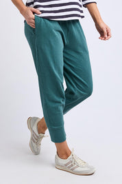 A model wearing the Fundamental Brunch Cotton Pant in colour Teal (Green), from the front, cropped image