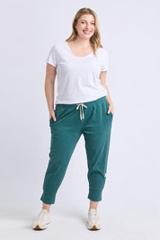 A model wearing the Fundamental Brunch Cotton Pant in colour Teal (Green), from the front, showing the whole outfit