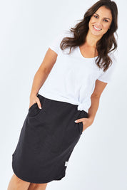 Model Shadae wearing size 10 of the Fundamental Isla Skirt in colour Black (Black), from the front, cropped image