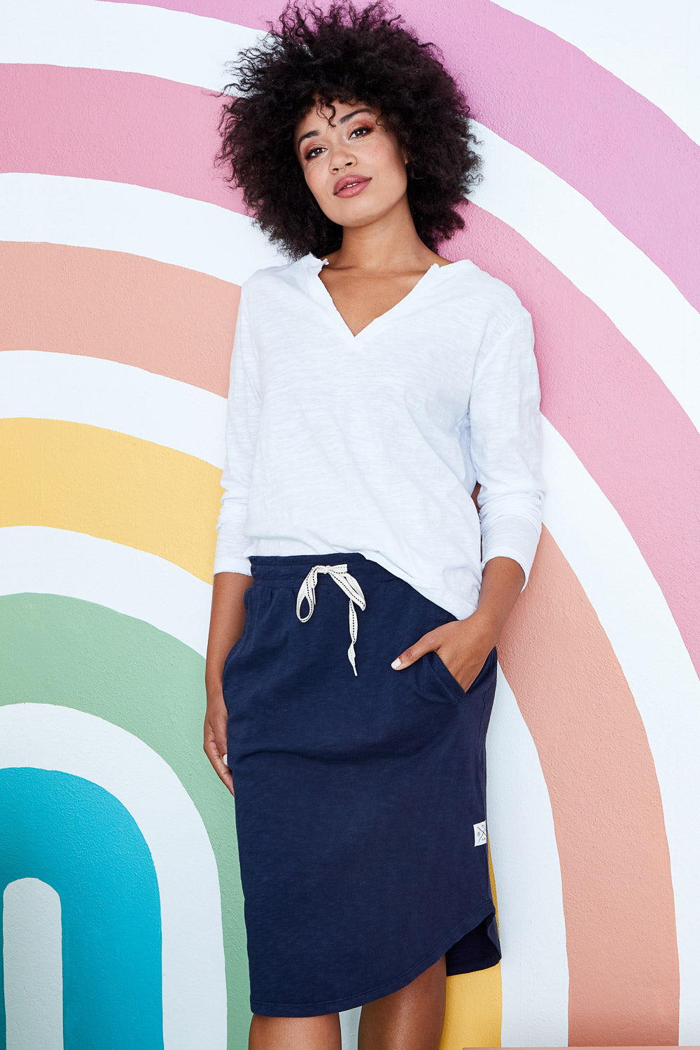 Model Olivia wearing size 10 of the Fundamental Isla Skirt in colour Navy (Blue), from the front, showing the whole outfit