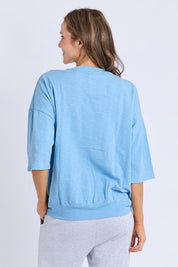A model wearing the Fundamental Mazie Cotton Sweat Top in colour Duskblue (Blue), from the back