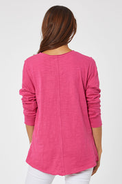 Model Cara wearing size 10 of the Fundamental Coles Bay Henley in colour Raspberry (Pink), from the back