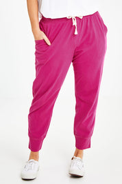 Model Laura wearing size 14 of the Fundamental Wash Out Pant in colour Plum (Pink), from the front, cropped image