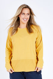 Model Jess wearing size 14 of the Fundamental Rib Long Sleeve Tee in colour Mustard, from the front, cropped image
