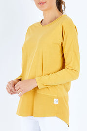 Model Madeline wearing size 10 of the Fundamental Rib Long Sleeve Tee in colour Mustard, from the front, cropped image