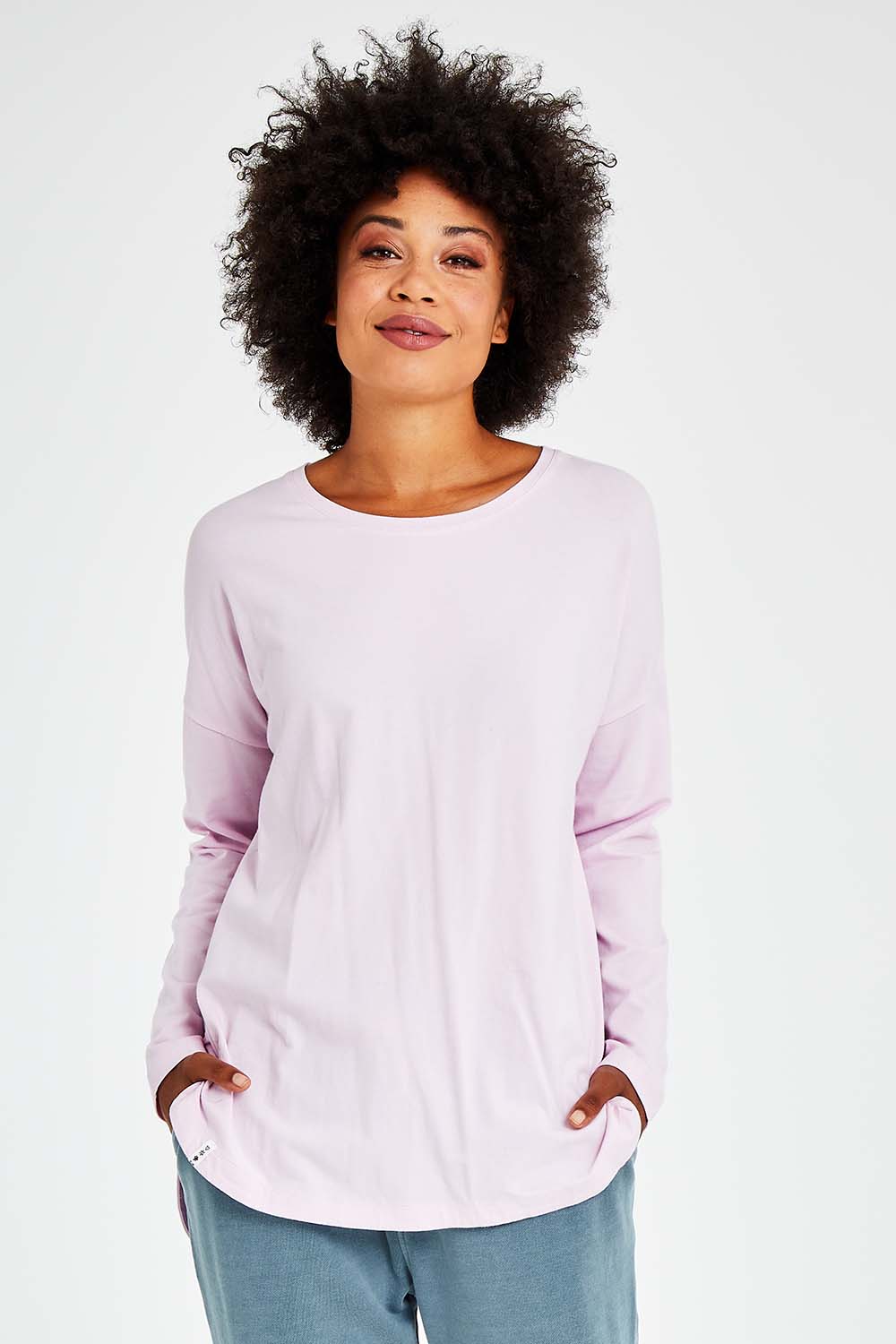 Model Olivia wearing size 10 of the Fundamental Society L/S Tee in colour Pink (Pink), from the front, cropped image
