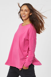 Model Cara wearing size 10 of the Fundamental Society L/S Tee in colour Raspberry (Pink), from the front, cropped image