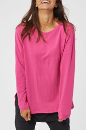Model Cara wearing size 10 of the Fundamental Society L/S Tee in colour Raspberry (Pink), from the front, cropped image