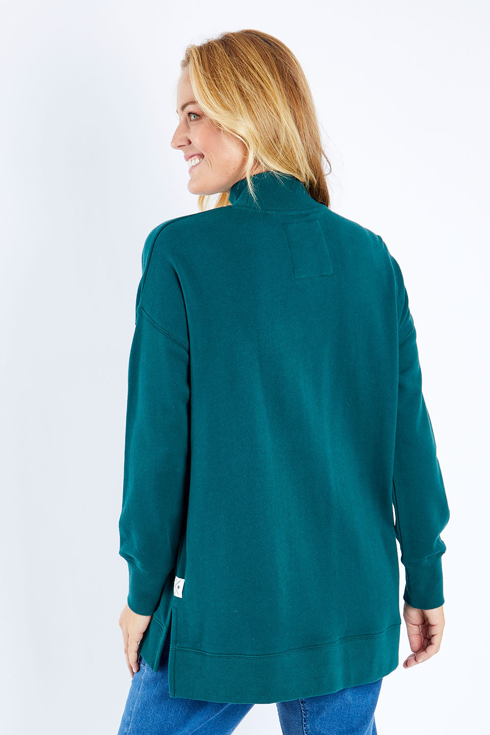 Model Bianca wearing size 10 of the Fundamental Tara High Neck Jumper in colour Alpine (Green), from the back