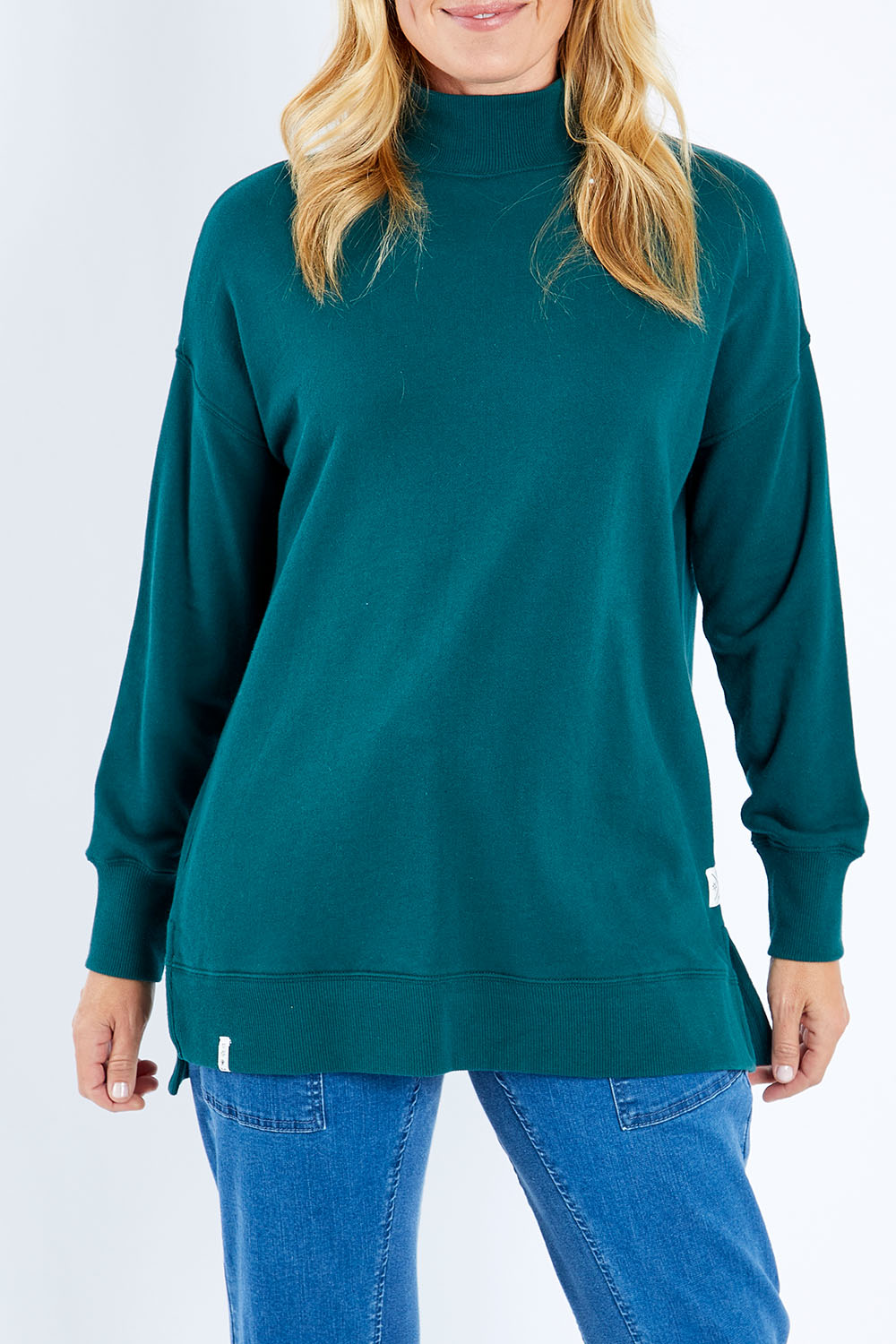 Model Bianca wearing size 10 of the Fundamental Tara High Neck Jumper in colour Alpine (Green), from the front, cropped image