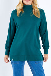 Model Bianca wearing size 10 of the Fundamental Tara High Neck Jumper in colour Alpine (Green), from the front, cropped image