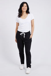 A model wearing the Fundamental Lobby Pant in colour Black (Black), from the front, showing the whole outfit