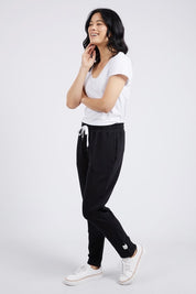 Model Miranda wearing size 10 of the Fundamental Lobby Pant in colour Black (Black), from the front, showing the whole outfit