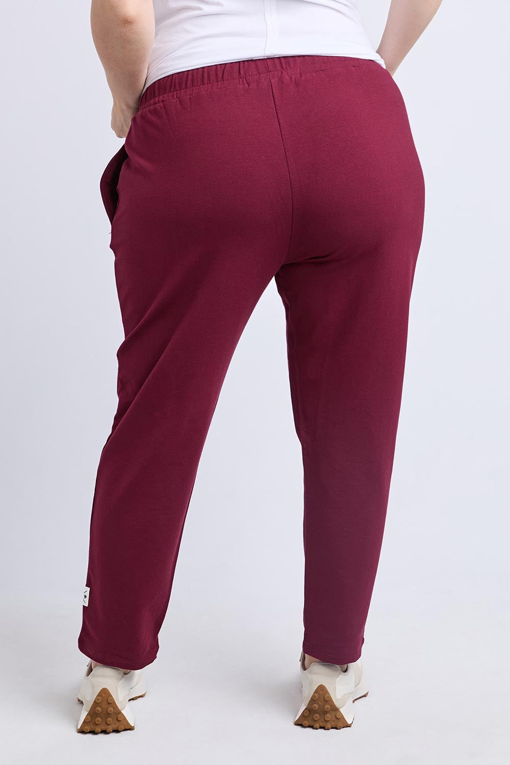 A model wearing the Fundamental Lobby Pant in colour Plum (Purple), from the back