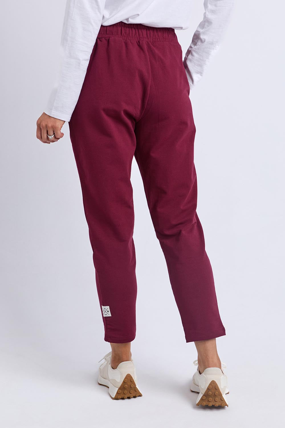A model wearing the Fundamental Lobby Pant in colour Plum (Purple), from the back