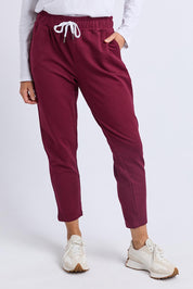 A model wearing the Fundamental Lobby Pant in colour Plum (Purple), from the front, cropped image