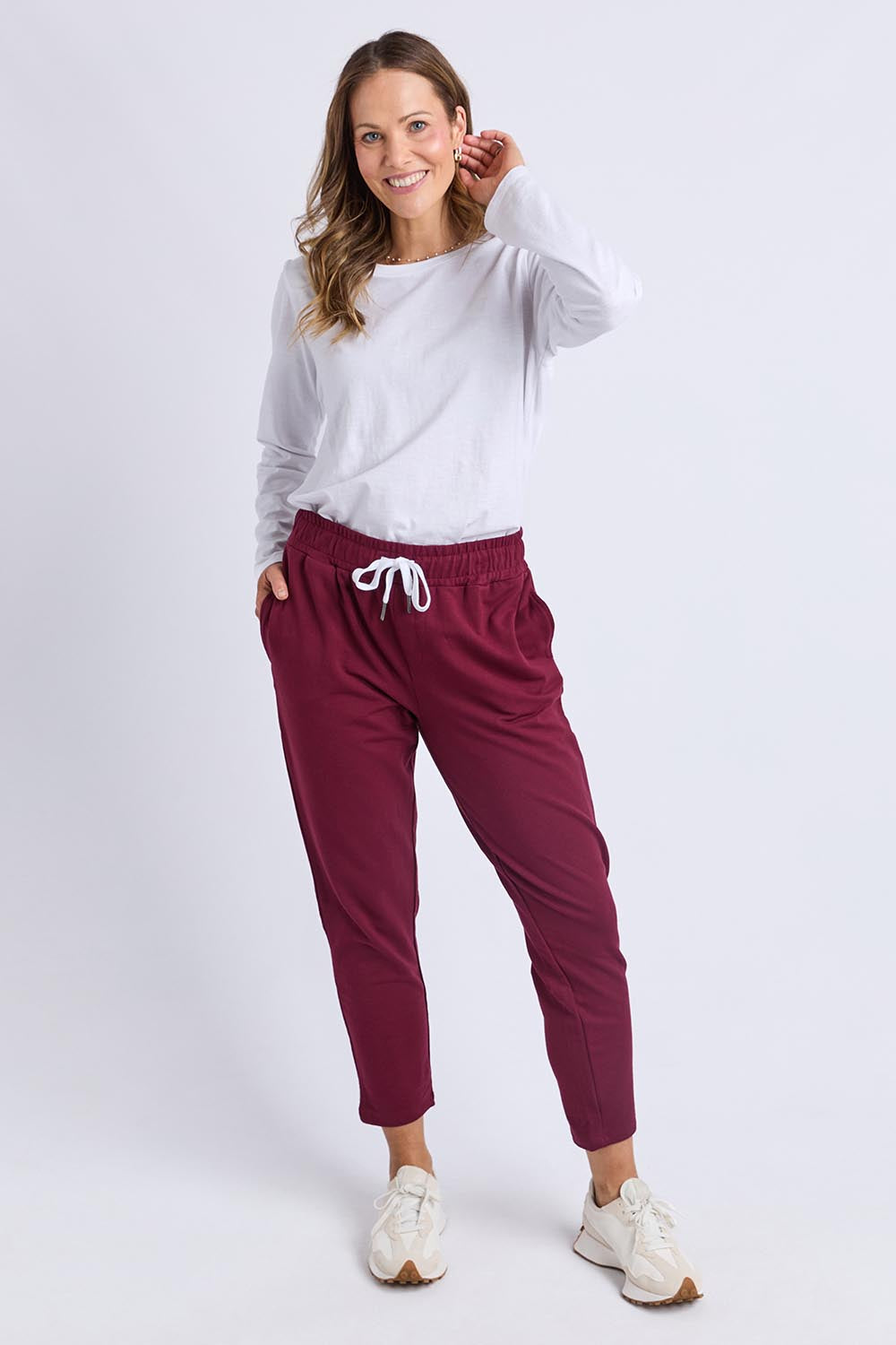 A model wearing the Fundamental Lobby Pant in colour Plum (Purple), from the front, showing the whole outfit