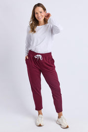 A model wearing the Fundamental Lobby Pant in colour Plum (Purple), from the front, showing the whole outfit