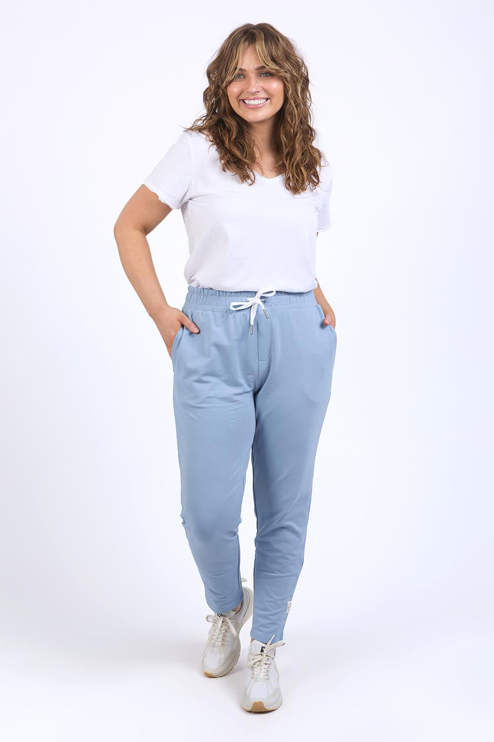A model wearing the Fundamental Lobby Pant in colour Steelblue (Blue), from the front, showing the whole outfit