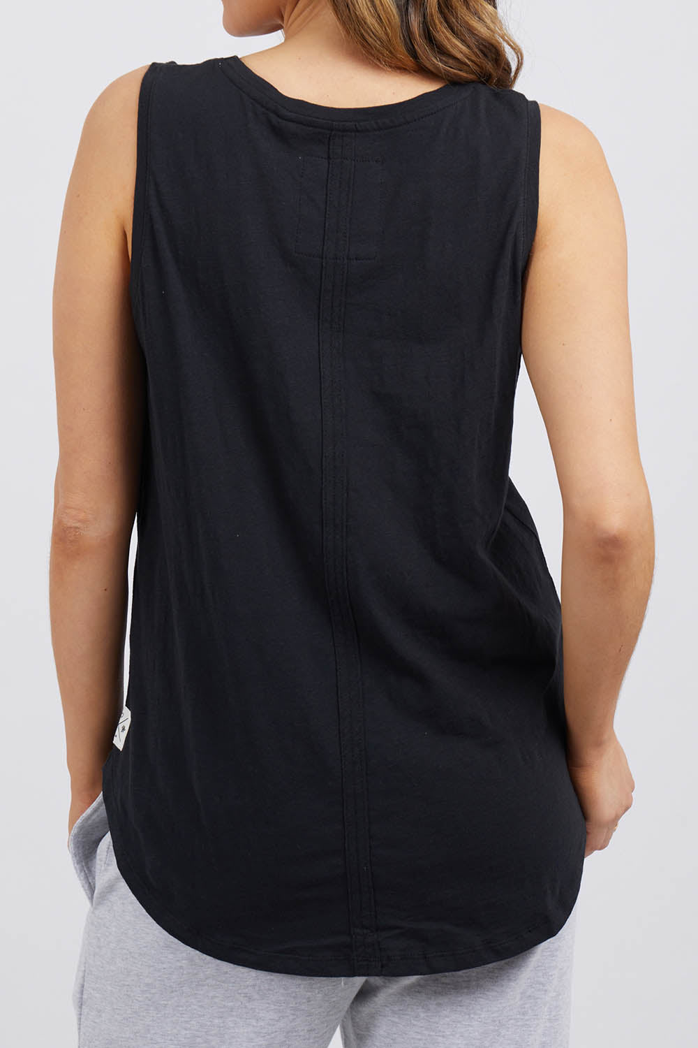 A model wearing the Fundamental Scoop Tank in colour Black (Black), from the back