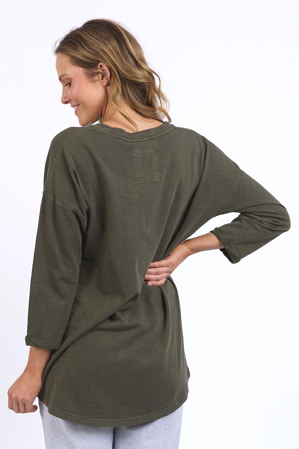A model wearing the Fundamental Annie 3/4 Sleeve Tee in colour Basil (Green), from the back