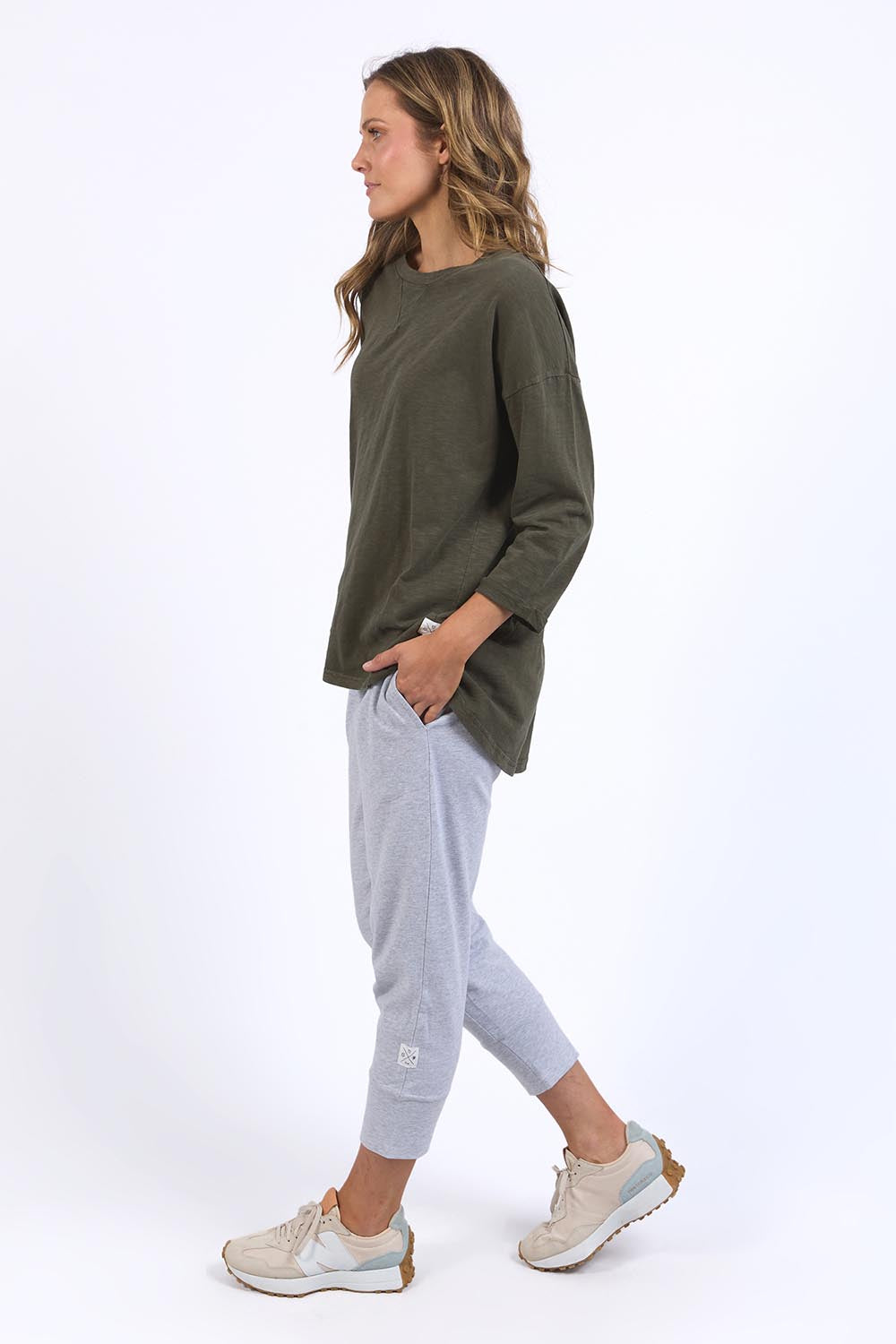A model wearing the Fundamental Annie 3/4 Sleeve Tee in colour Basil (Green), from the front, showing the whole outfit