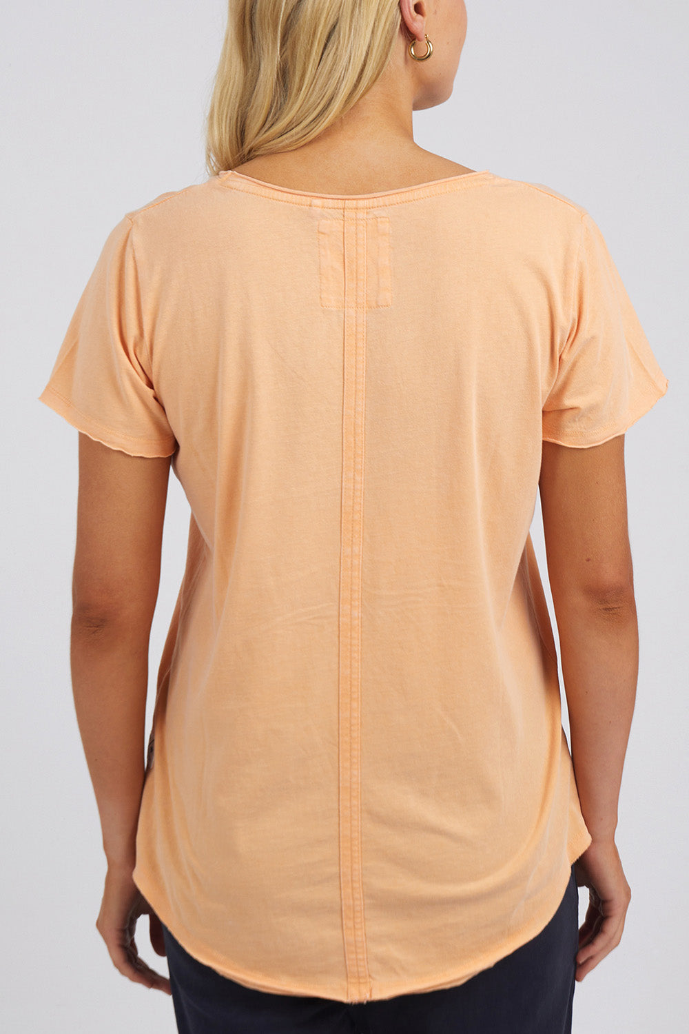 A model wearing the Fundamental Cloud Vee Tee in colour Papaya, from the back