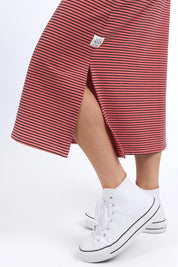 A model wearing the Fundamental Cotton Travel Skirt in colour Watermelon (Red), from the front, cropped image