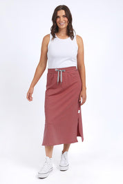 A model wearing the Fundamental Cotton Travel Skirt in colour Watermelon (Red), from the front, showing the whole outfit