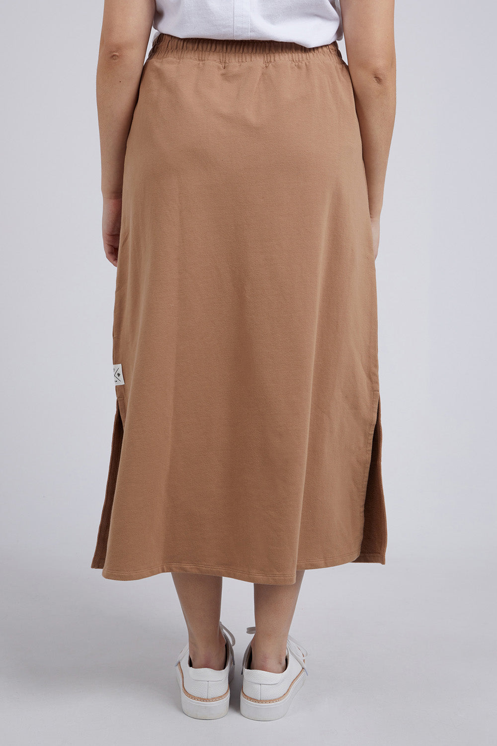 A model wearing the Fundamental Travel Skirt in colour Mocha, from the back
