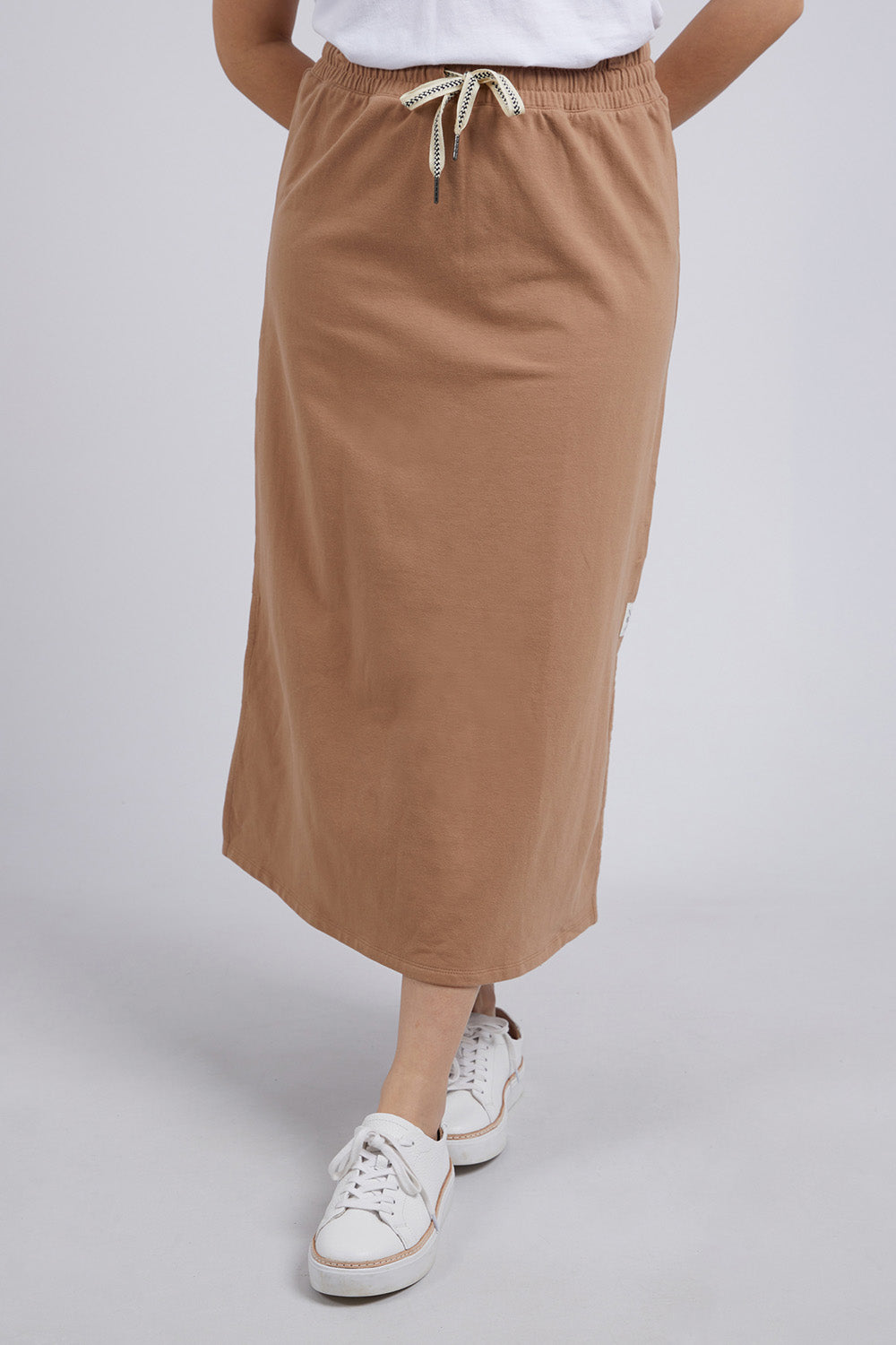 A model wearing the Fundamental Travel Skirt in colour Mocha, from the front, cropped image