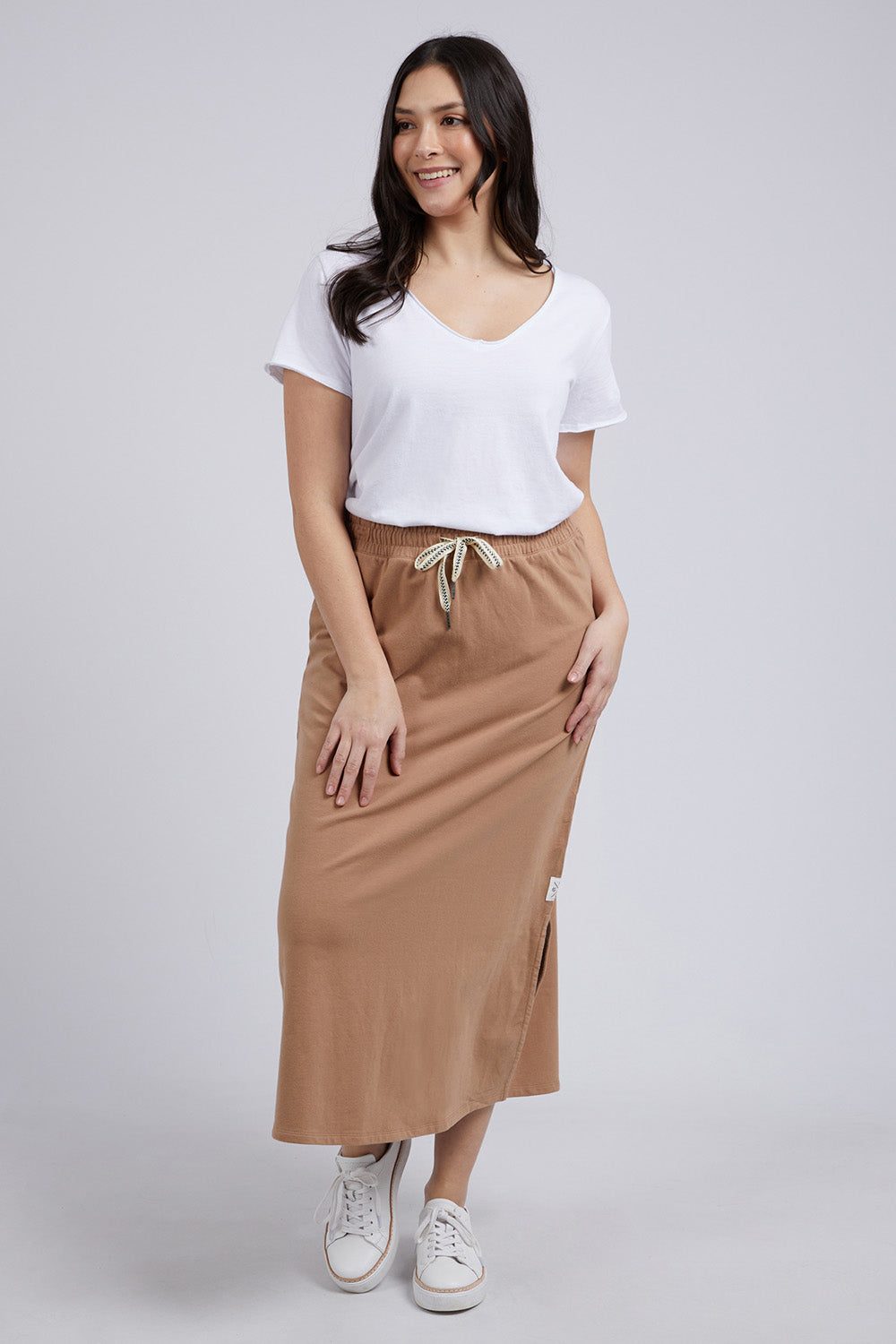 A model wearing the Fundamental Travel Skirt in colour Mocha, from the front, showing the whole outfit