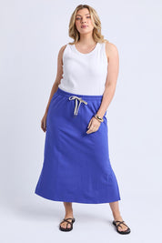 A model wearing the Fundamental Travel Skirt in colour Oceanblue (Blue), from the front, showing the whole outfit