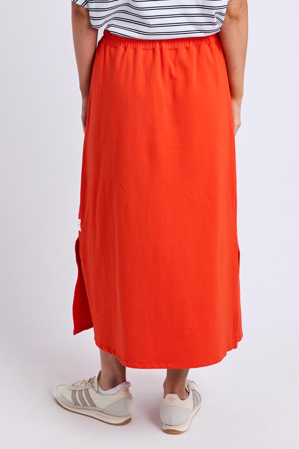 Model Genericm wearing size sample of the Fundamental Travel Skirt – Tangello in colour Tangello, from the back