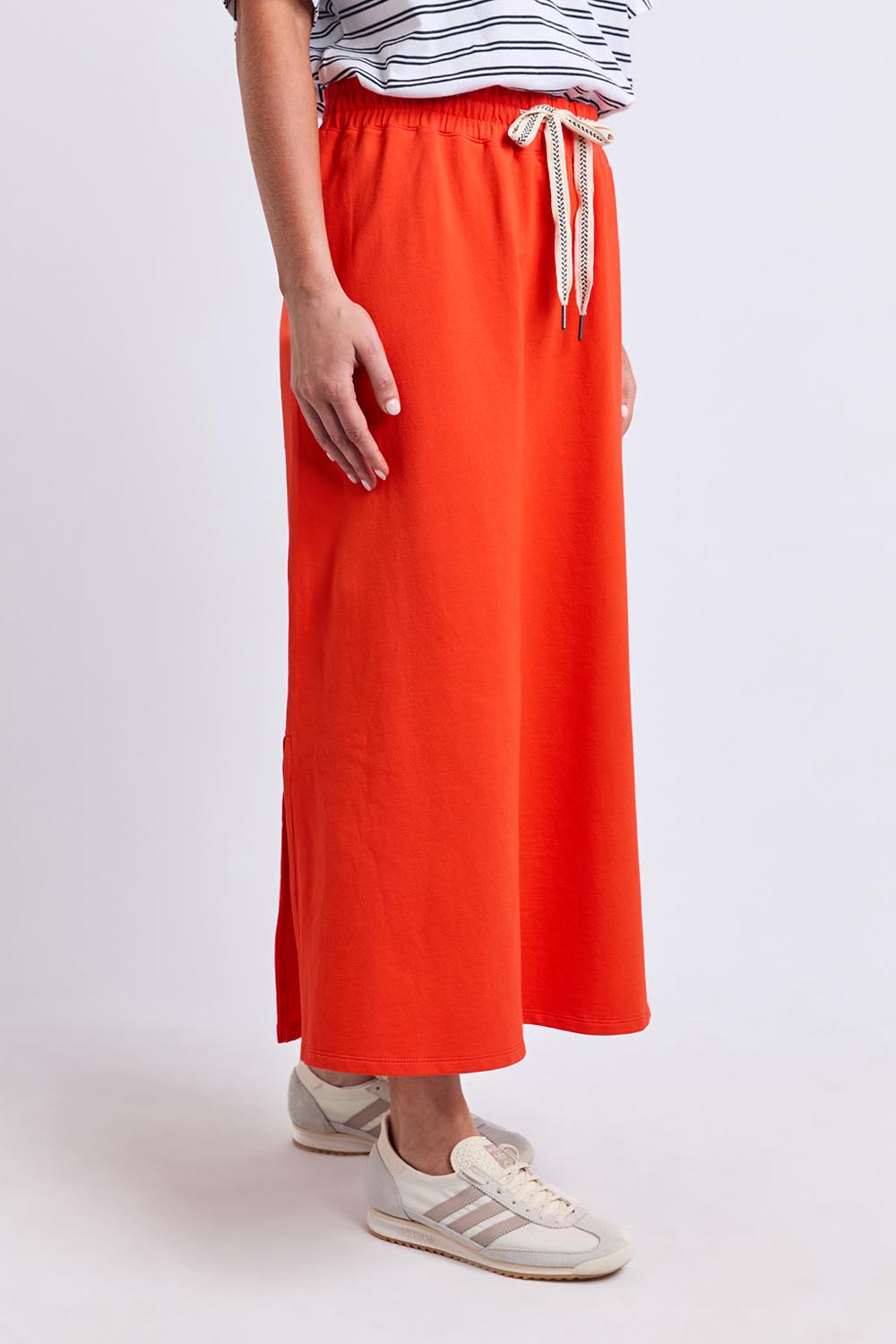 Model Genericm wearing size sample of the Fundamental Travel Skirt – Tangello in colour Tangello, in a cropped view