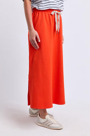 Model Genericm wearing size sample of the Fundamental Travel Skirt – Tangello in colour Tangello, in a cropped view