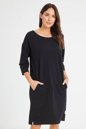 Model Madeline wearing size 10 of the Fundamentals Carolina Fleece Dress in colour Black (Black), from the front, cropped image