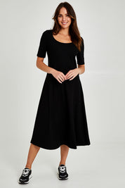 Model Madeline wearing size 10 of the Fundamental Marguerite Dress in colour Black (Black), from the front, showing the whole outfit