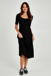 Model Madeline wearing size 10 of the Fundamental Marguerite Dress in colour Black (Black), from the front, showing the whole outfit