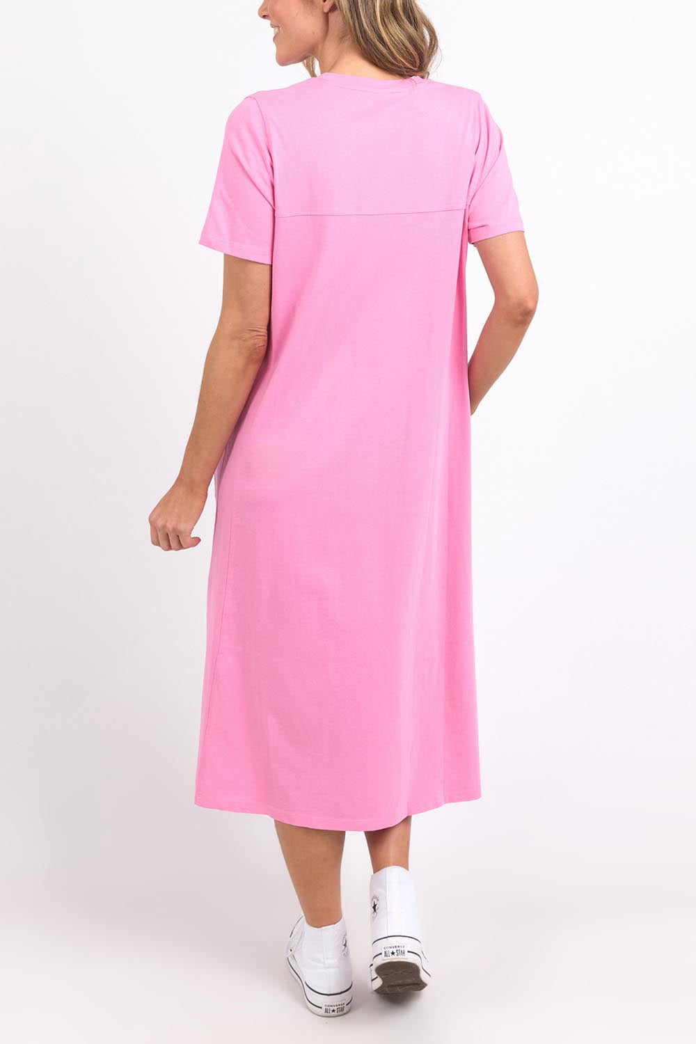 A model wearing the Fundamental Adira Dress in colour Strawberry (Pink), from the back