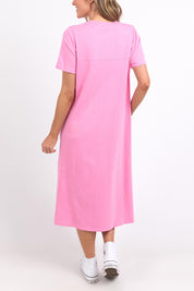 A model wearing the Fundamental Adira Dress in colour Strawberry (Pink), from the back